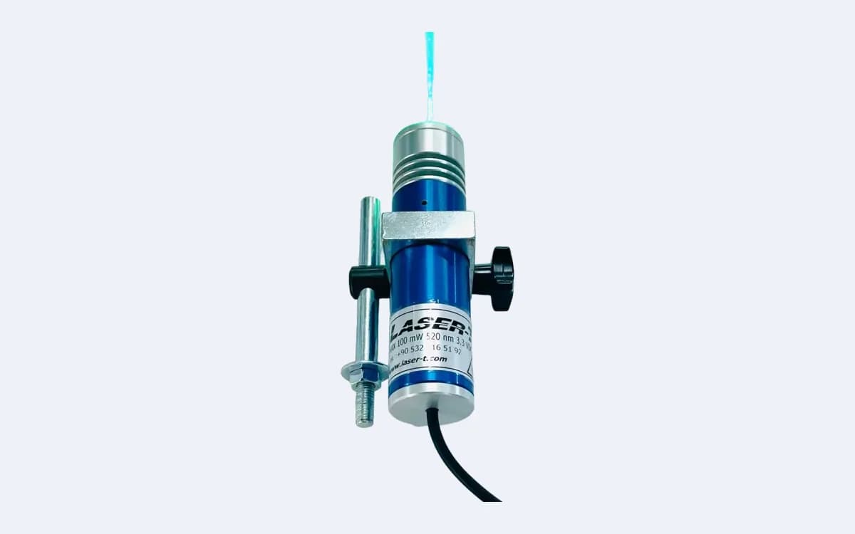TM100L35 yeşil çizgi lazer dik duruşta — lens yukarıda yeşil ışın veriyor, montaj mili solda, sıkma topuzu sağda