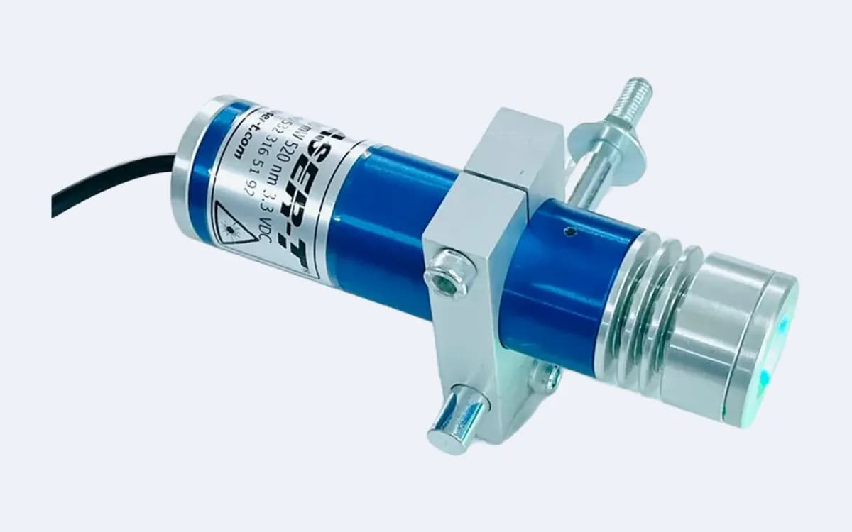 TOD100C35 yeşil daire lazer çapraz açıdan — kanatlı lens başlığı sağ altta yeşil yanıyor, alüminyum tutucu ortada, kablo solda